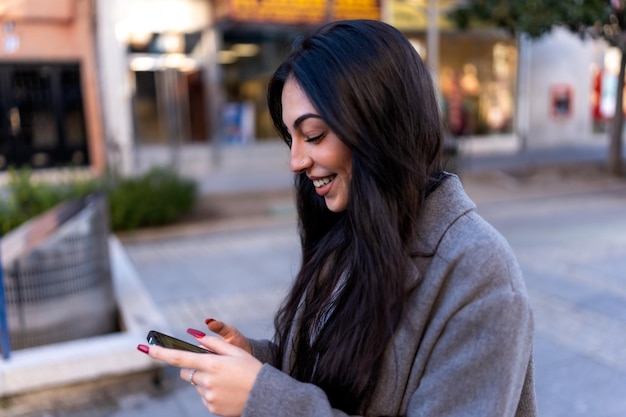 Mujer alegre charlando en el teléfono inteligente durante la caminata