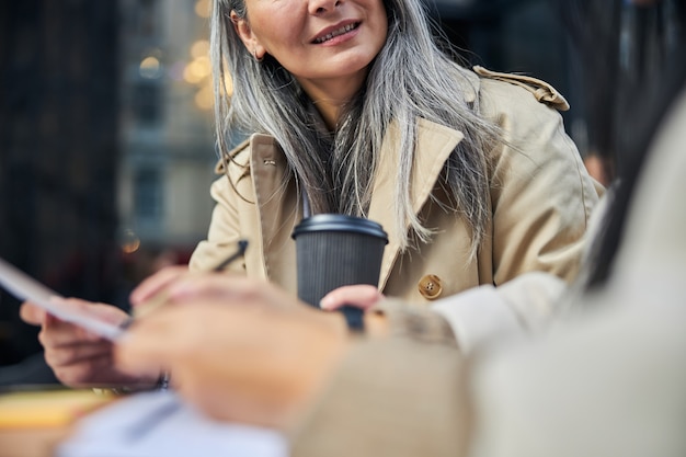 Mujer alegre estudiando documentos con un colega en la cafetería al aire libre