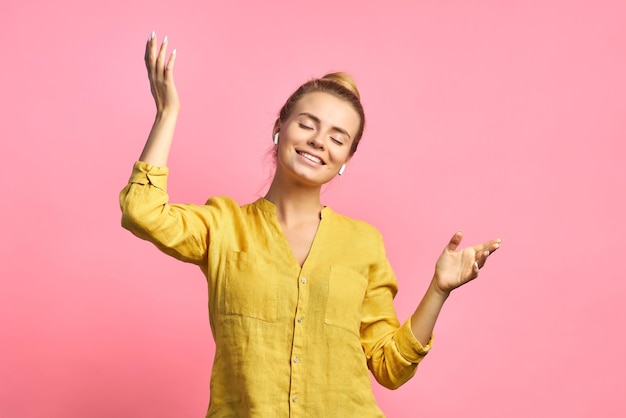 Una mujer alegre y expresiva escucha música en los auriculares disfruta de melodías agradables tiene buen humor baila sonrisas despreocupadas