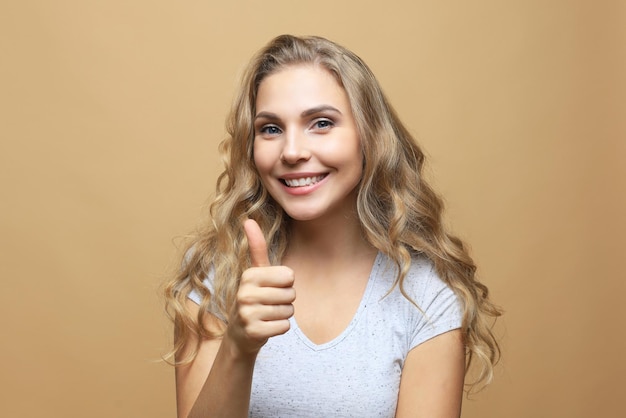 Mujer alegre feliz joven que muestra el pulgar para arriba.