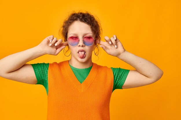 Mujer alegre gafas de sol multicolores en la cara posando mueca vista recortada inalterada