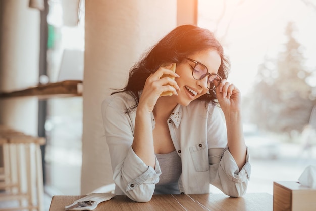 Mujer alegre hablando por teléfono en el café