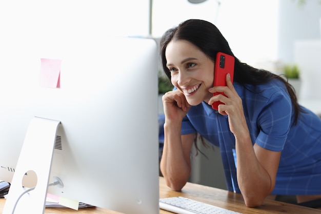 Mujer alegre hablando por teléfono celular y mirando la pantalla de la computadora concepto de consultoría remota