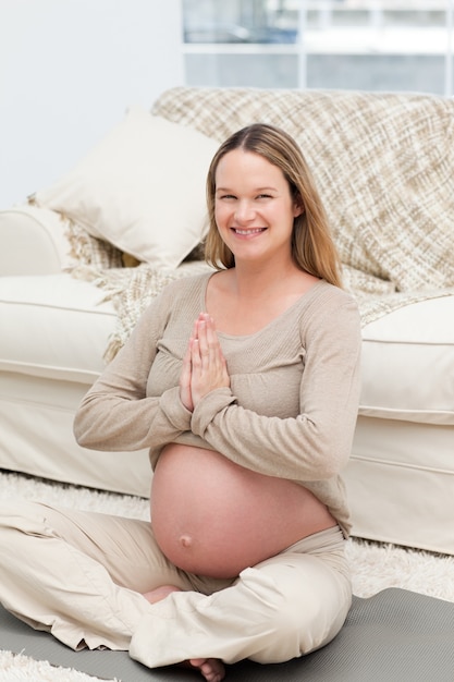 Foto mujer alegre haciendo postura de yoga en el piso de la sala de estar