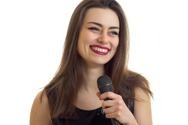 Mujer alegre con hermoso maquillaje sonriendo con micrófono en manos aislado sobre fondo blanco.