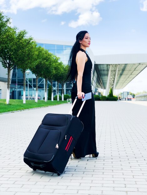 Mujer alegre joven con una maleta. El de viajes y trabajo