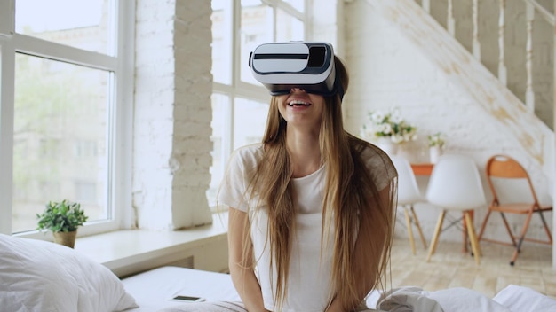 Mujer alegre joven que usa auriculares de realidad virtual viendo una película de video 360 VR