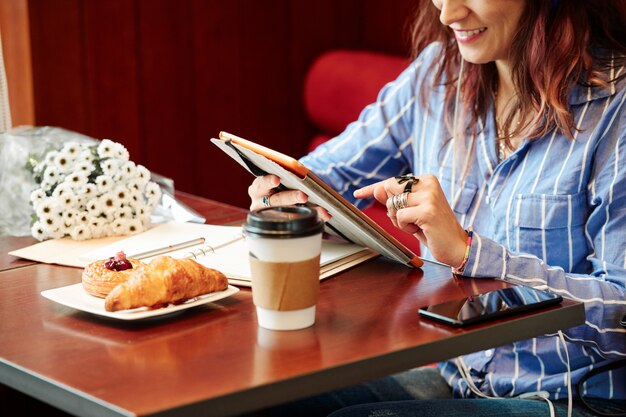 Mujer alegre en la mesa de café con tablet PC