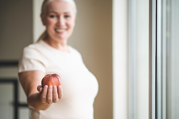 Mujer alegre mostrando su fruta saludable favorita ante la cámara