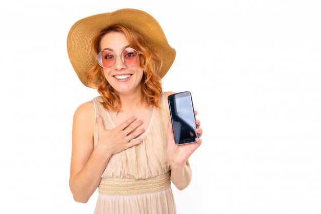 La mujer alegre con el pelo rojo claro en sonrisas hermosas del vestido, imagen aislada en el fondo blanco