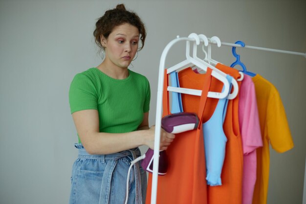 Mujer alegre planchando ropa en un armario colgador fondos aislados inalterados