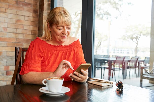 Mujer alegre que controla mensajes de texto