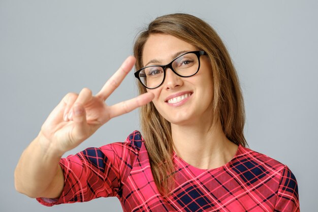 Mujer alegre que muestra el signo de la paz con sus dedos