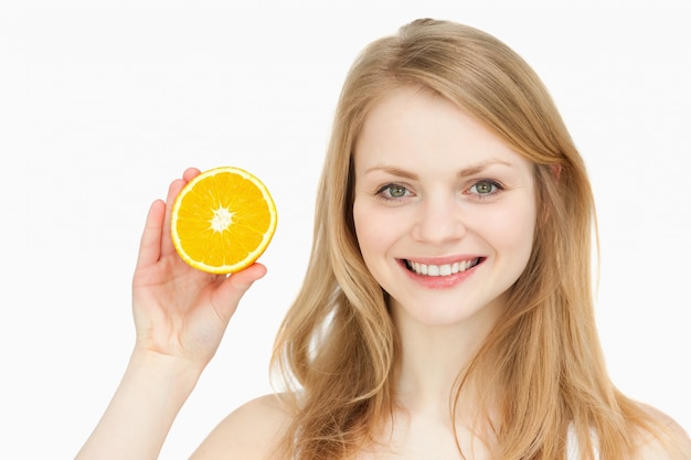 Mujer alegre que presenta una naranja