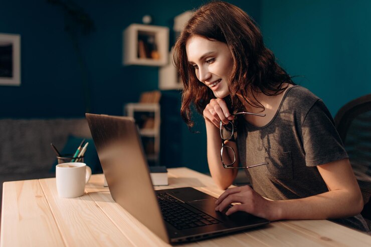 Mujer alegre que trabaja en la computadora portátil a la hora de la tarde