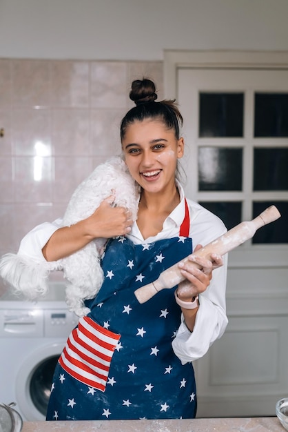 Mujer alegre con un rodillo y un perro maltés blanco