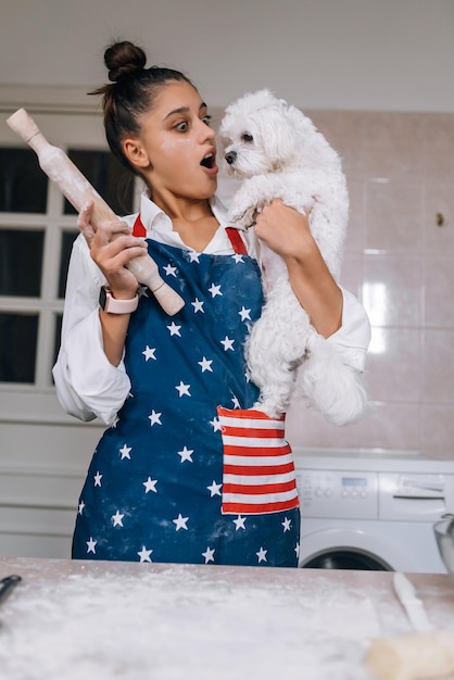 Mujer alegre con un rodillo y un perro maltés blanco