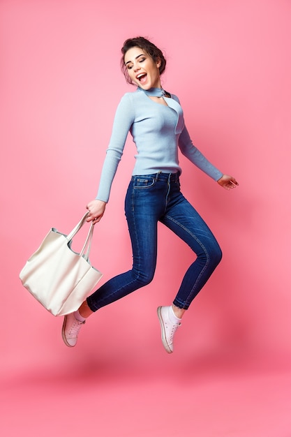 Mujer alegre saltando con bolso