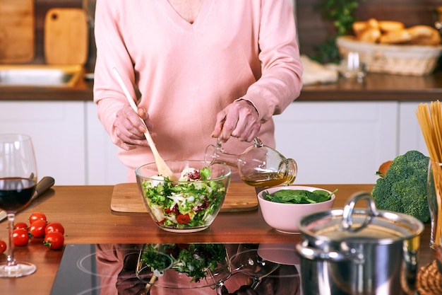 Mujer alegre senior está cocinando en la cocina moderna