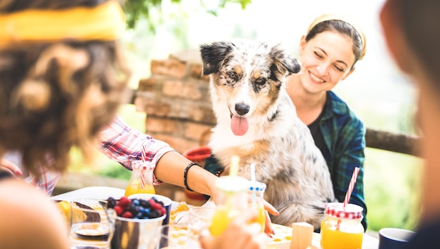 Mujer alegre sentada con el perro mientras come y bebe en un restaurante al aire libre