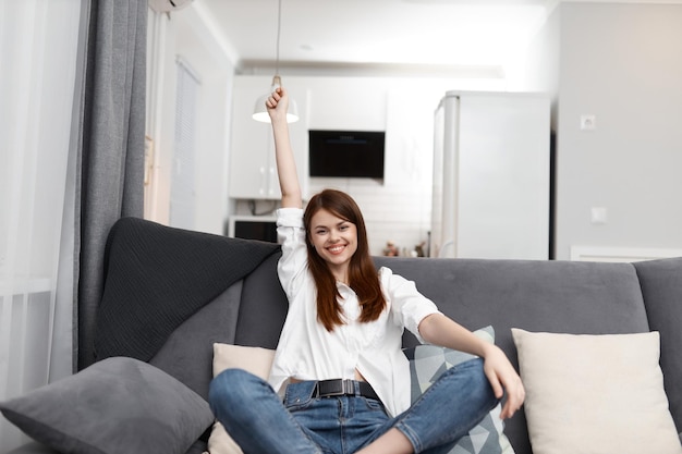 Mujer alegre sentada en el sofá Comfort apartamento interior ocio foto de alta calidad