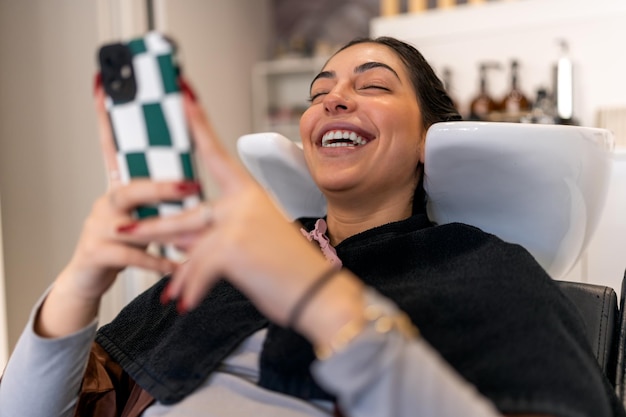 Mujer alegre con smartphone en salón de belleza