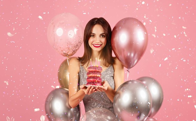 Mujer alegre con una sonrisa radiante celebrando con donuts coronados con velas de cumpleaños