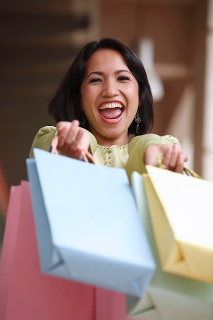 Foto mujer alegre sosteniendo bolsas de compras mientras está de pie en el pasillo