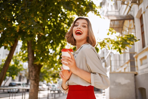 Mujer alegre con una taza de café al aire libre en verano