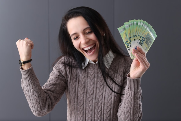 Mujer alegre tiene euro en su mano. Concepto de juego y trabajo remoto