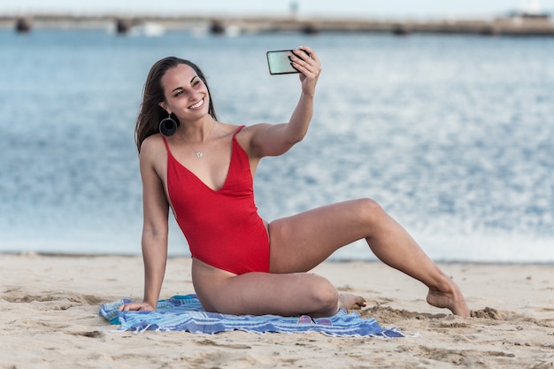 Mujer alegre tomando selfie cerca del mar