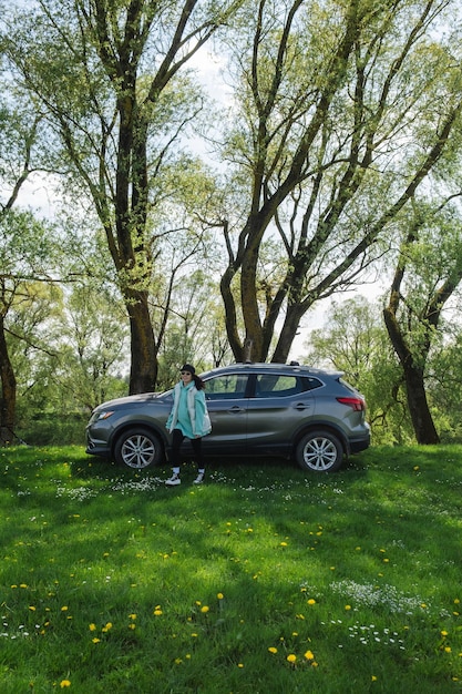 Foto una mujer se aleja de un automóvil estacionado en un césped verde en la naturaleza