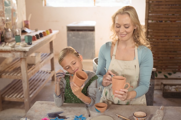 Mujer alfarera y niña pintando en taller de cerámica