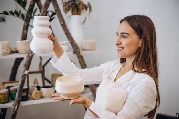 Mujer alfarera sosteniendo tazones de cerámica en la tienda