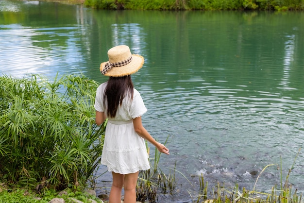 Mujer alimenta a los peces de mierda en el lago de agua en el paisaje natural