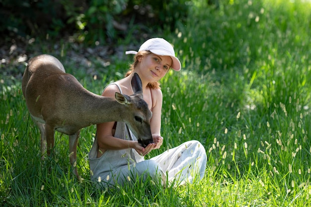 La mujer alimenta la unidad del ciervo leonado con la naturaleza concepto de animales salvajes niña alimentando al animal bambi en el parque