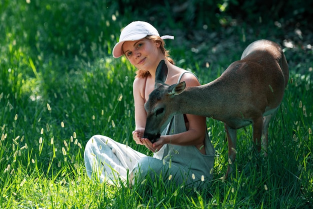 La mujer alimenta la unidad del ciervo leonado con la naturaleza concepto de animales salvajes niña alimentando al animal bambi en el parque