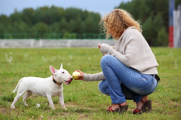 Una mujer alimentando a un perro con un hueso.