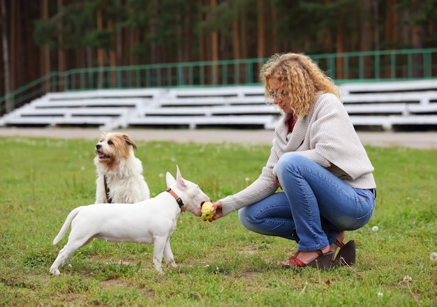 Una mujer alimentando a un perro con un hueso.