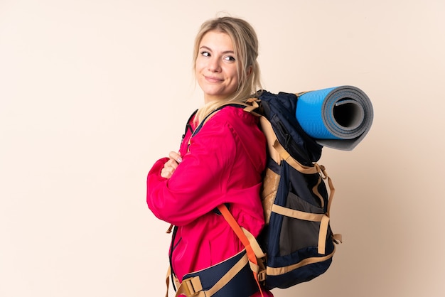 Mujer alpinista con una mochila grande sobre pared aislada riendo