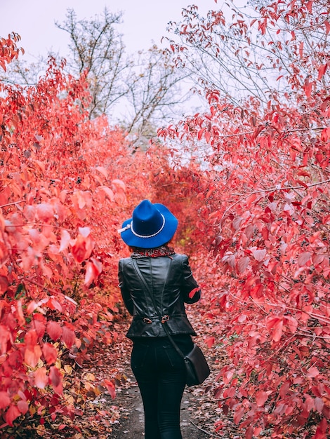 Mujer alta está caminando en el parque con larga avenida roja