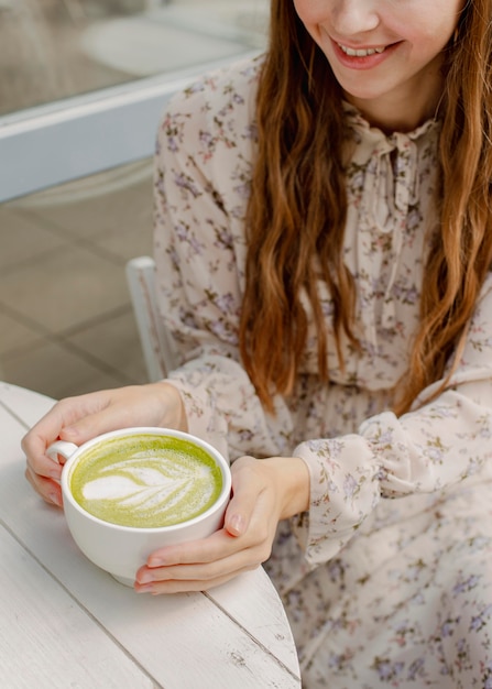 Foto mujer de alto ángulo con taza de café con leche matcha