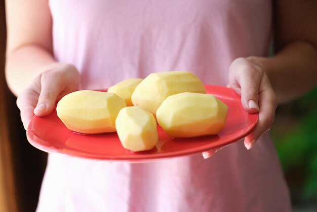 Mujer ama de casa sosteniendo un plato de papas peladas en sus manos de cerca