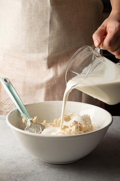 Mujer añadiendo crema de grasa en el tazón de tarta de queso vasco tarta de queso quemado