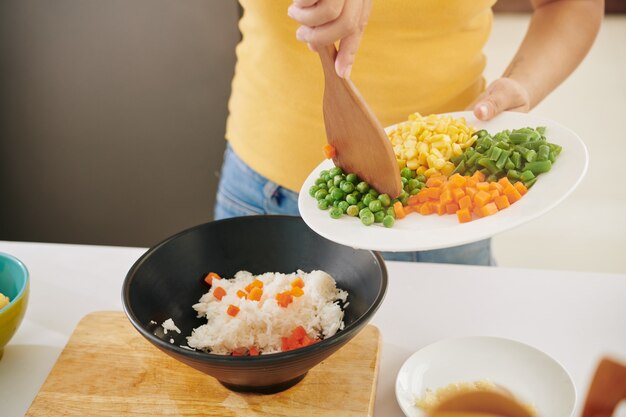 Mujer añadiendo verduras al arroz