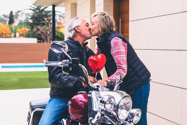 Foto mujer anciana, besar, hombre, en, motocicleta