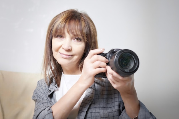 Foto mujer anciana con cámara negra con una lente grande en el interior del estudio un profesional