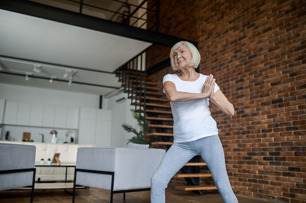 Mujer anciana delgada haciendo yoga en casa