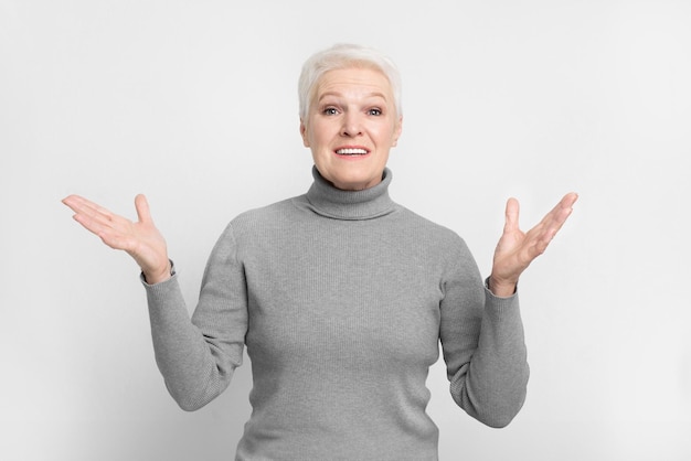 Foto mujer anciana encogiéndose de hombros con confusión en el fondo gris