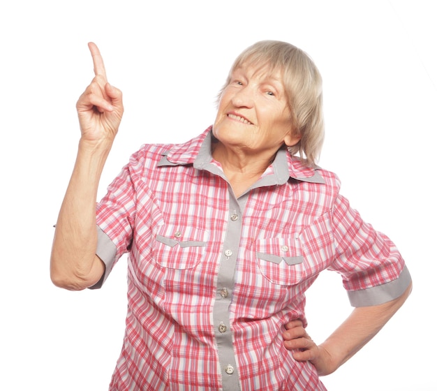 Foto mujer anciana feliz apuntando hacia arriba aislada sobre un fondo blanco